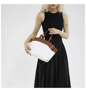 Detail of white and brown contrast handbag with smooth texture and sturdy handles
