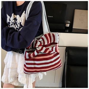Detail of knitted striped tote bag with large 3D bow decoration and shoulder strap