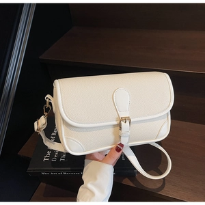 Macro detail of creamy white lychee grain leather handbag with gold metal buckle