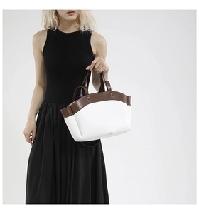 Chic two-tone handbag in white and brown leather held by a model in a black dress