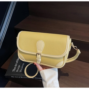 Detailed view of yellow lychee grain leather bag with contrast stitching on wooden steps