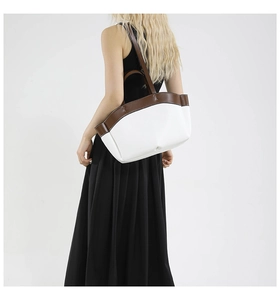 Rear view of a model styling a large color-block tote bag with brown leather handles