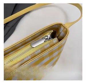Detail of yellow checkered tote bag showing silver metal zipper and leather strap
