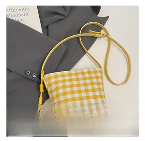 Close-up of yellow checkered canvas bag with shoulder strap and woven knot detail