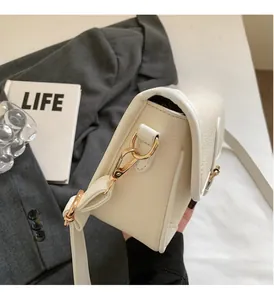 Close-up of cream-colored pebble leather texture and gold metal hook on the shoulder bag