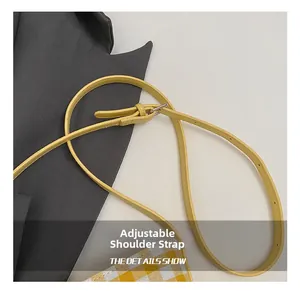 Detail of adjustable yellow shoulder strap with silver metal buckle on checkered tote bag