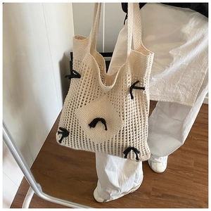 Détail du sac fourre-tout au crochet crème avec nœuds noirs et motif en maille ajourée