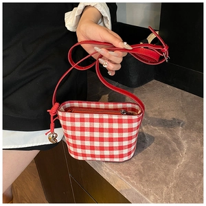 Detail of red checkered canvas tote bag with leather strap and silver heart pendant charm