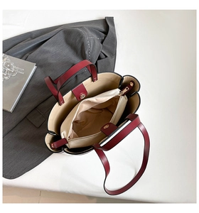 Detailed view of dark red leather tote interior with beige canvas insert and magnetic buckle