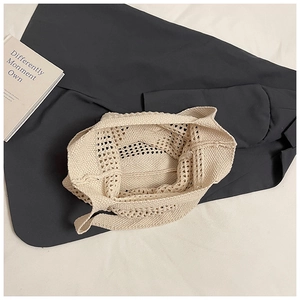Gros plan d'un sac cabas en crochet beige avec texture ajourée sur une veste grise