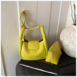 Close-up of vibrant yellow lychee grain leather handbag with matching zip pouch detail