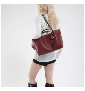 Model view of large burgundy matte leather tote bag with unique wood ring pendant