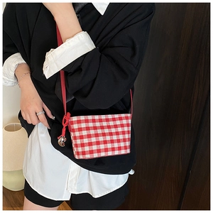 Detail of red gingham canvas bag with a silver moon charm and knot shoulder strap
