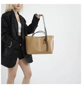Detail of khaki leather tote bag featuring side fringe tassels and dual shoulder straps