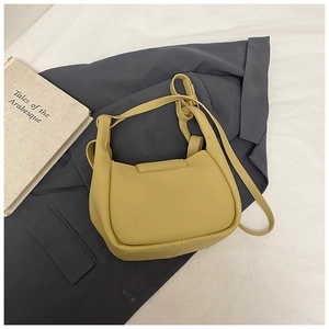 Top view of yellow half-moon crossbody bag on a dark suit with a decorative book