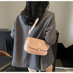 Pink litchi texture leather crossbody bag shown on model wearing a grey blazer