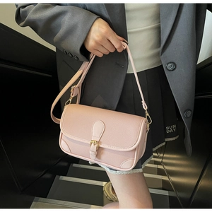 Detail of light pink pebble leather underarm bag featuring elegant gold metal hardware buckle