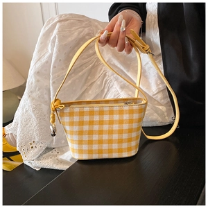 Detail of yellow gingham canvas bucket bag with silver ball charm and zip closure