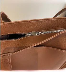 Close-up of a silver zipper and pebble grain leather on a brown tote bag detail