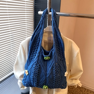 Sac à main en tricot bleu marine avec fleurs en crochet sur un cintre minimaliste