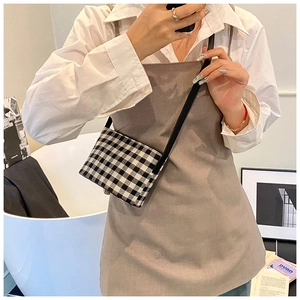 Close-up of a mini black and white checkered canvas crossbody bag with a slim strap