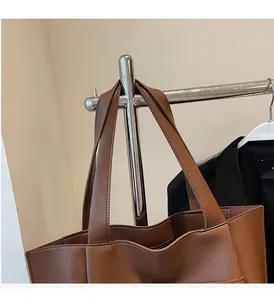 Detail shot of wide comfortable handle and fine leather texture of the brown tote bag