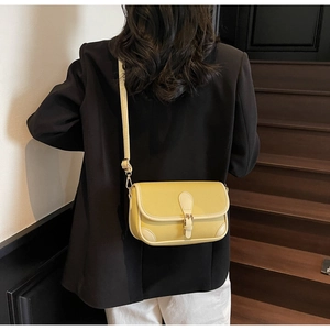 Detail of yellow pebbled leather crossbody bag with vintage buckle on a shoulder strap