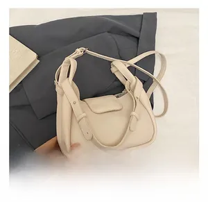 Detail view of beige pebbled leather shoulder bag showing metal rivets and flap closure