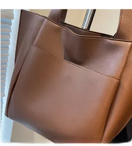 Detail shot of brown lychee grain leather tote bag showing texture and side pocket