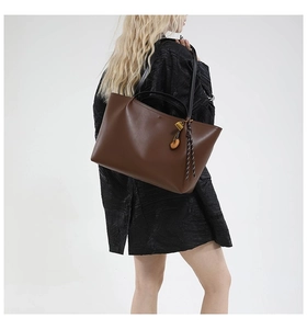 Detail view of large dark brown leather tote bag with gold padlock and woven cord charm