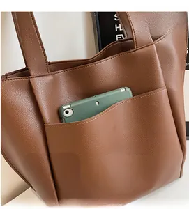 Detail view of brown tote bag featuring durable lychee grain leather and front pocket