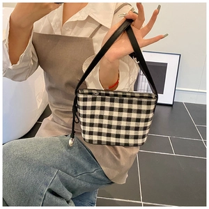 Detail of checkered canvas tote bag with silver ball pendant and zipper closure