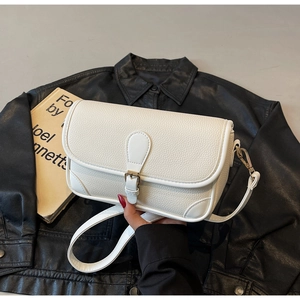 Detailed view of the creamy white lychee-patterned leather and metal buckle of the shoulder bag
