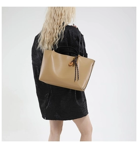 Detail view of khaki leather tote bag featuring handcrafted wooden circle charm and knot