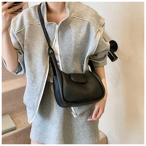 Detail of black pebbled leather crossbody bag shown in a stylish minimalist setting