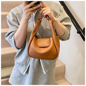 Detailed view of brown leather underarm bag with a fold-over handle and pebbled texture