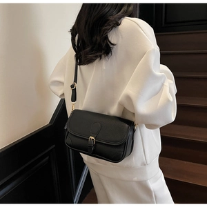 Detail of black pebbled leather crossbody bag featuring gold hardware and flap closure