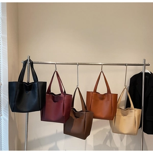 Collection of large leather tote bags in five colors hanging on a minimal display stand