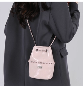 Pink quilted bucket bag with chain detail shown on shoulder for proportion reference