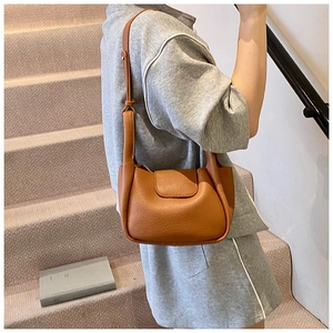 Close-up of caramel leather shoulder bag detail with adjustable strap and flap closure