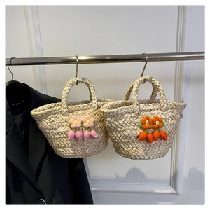 Dettaglio di borse tote in paglia intrecciata con fiori colorati all'uncinetto stile rustico