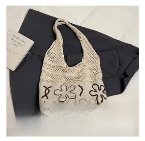 Detail of knitted tote bag with floral patterns and hollow mesh texture shown on a flat surface