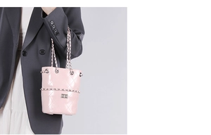 Pink quilted bucket bag detail with chain strap on a model wearing a grey blazer