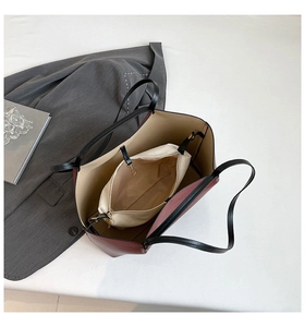 Detail view of large burgundy tote bag with beige inner pouch and slim black straps