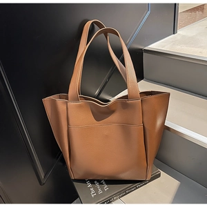 Detail of a large brown pebble grain leather tote bag featuring a spacious front pocket