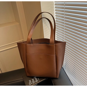 Detail of brown tote bag showing lychee leather texture and large front pocket design