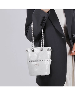 White quilted bucket bag with chain strap styled on a grey blazer for a modern look