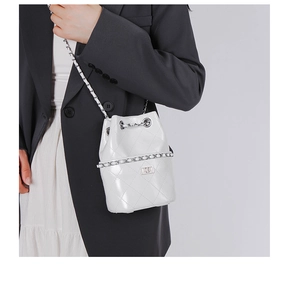 Close-up of white quilted leather bucket bag with silver chain strap and metal clasp