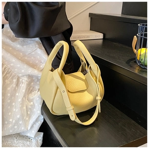 Close-up of pale yellow litchi grain leather texture and handle on a designer style bag