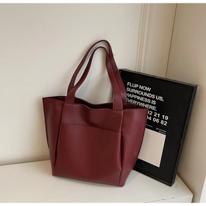 Close-up of burgundy leather tote bag featuring rich lychee texture and side pocket